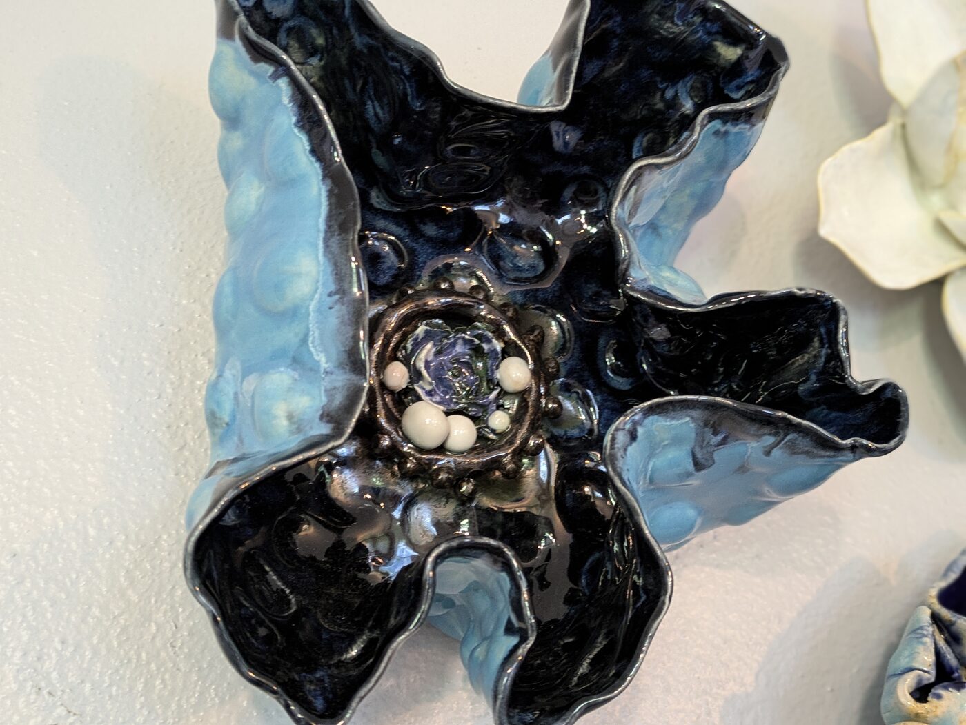Handbuilt ceramic splatter-glaze wall flower closeup